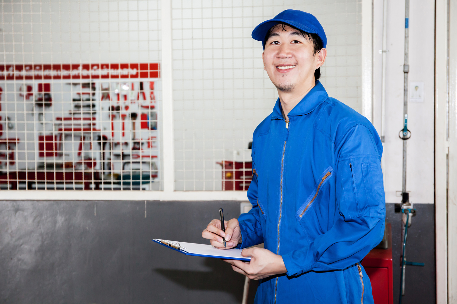 Asian car technician smiling in garage service